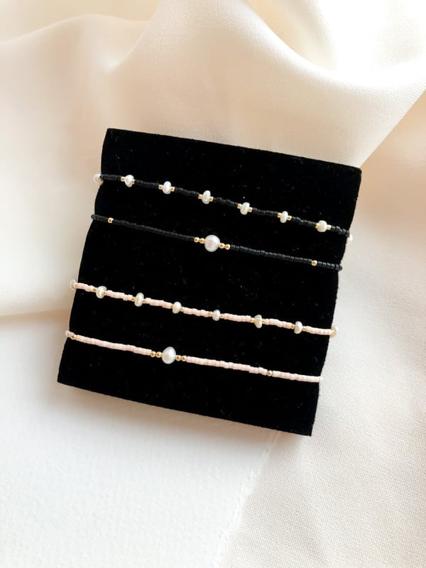 Pleciona czarna bransoletka z jedną perełką i złotymi koralikami
