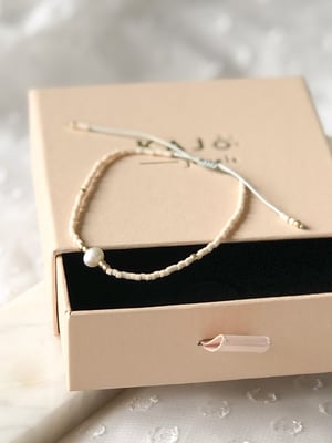 Pleciona beżowa bransoletka z jedną perełką i złotymi koralikami