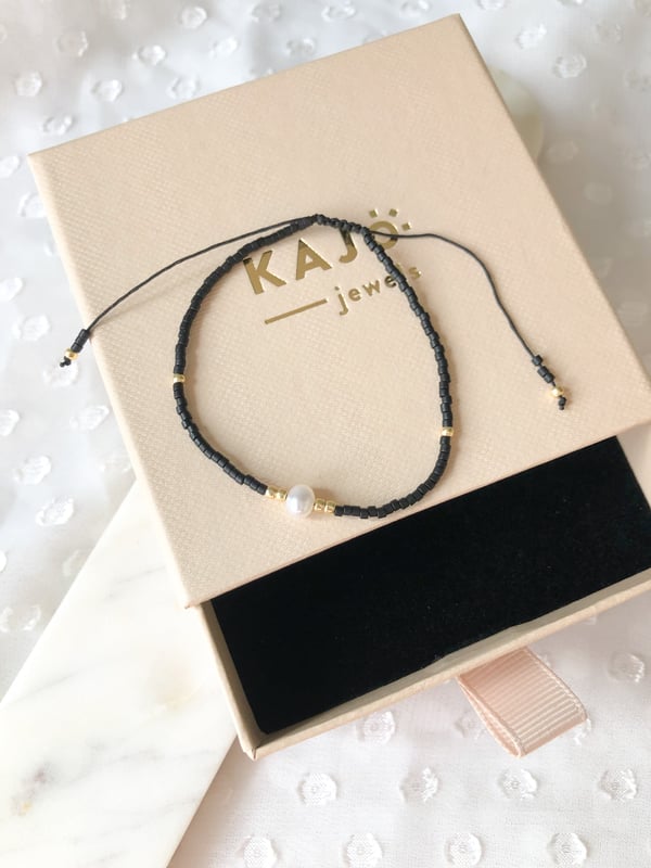 Pleciona czarna bransoletka z jedną perełką i złotymi koralikami