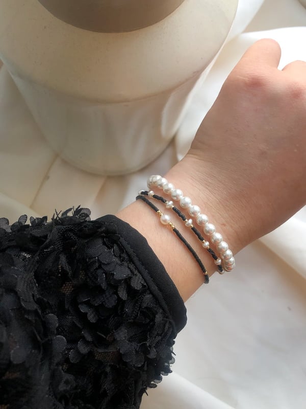 Pleciona czarna bransoletka z jedną perełką i złotymi koralikami