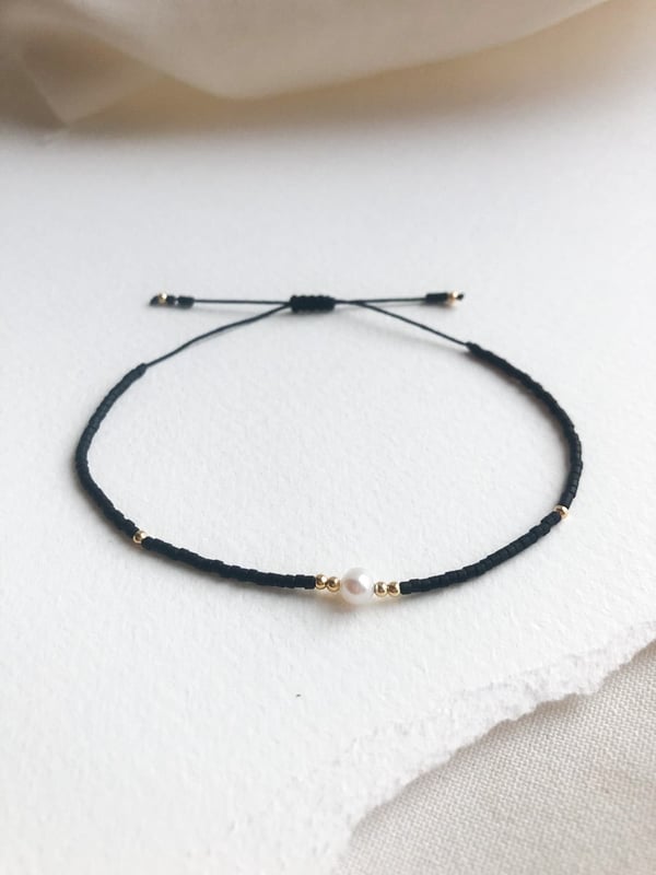 Pleciona czarna bransoletka z jedną perełką i złotymi koralikami