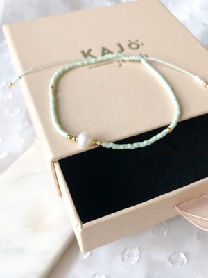 Pleciona miętowa bransoletka z jedną perełką i złotymi koralikami